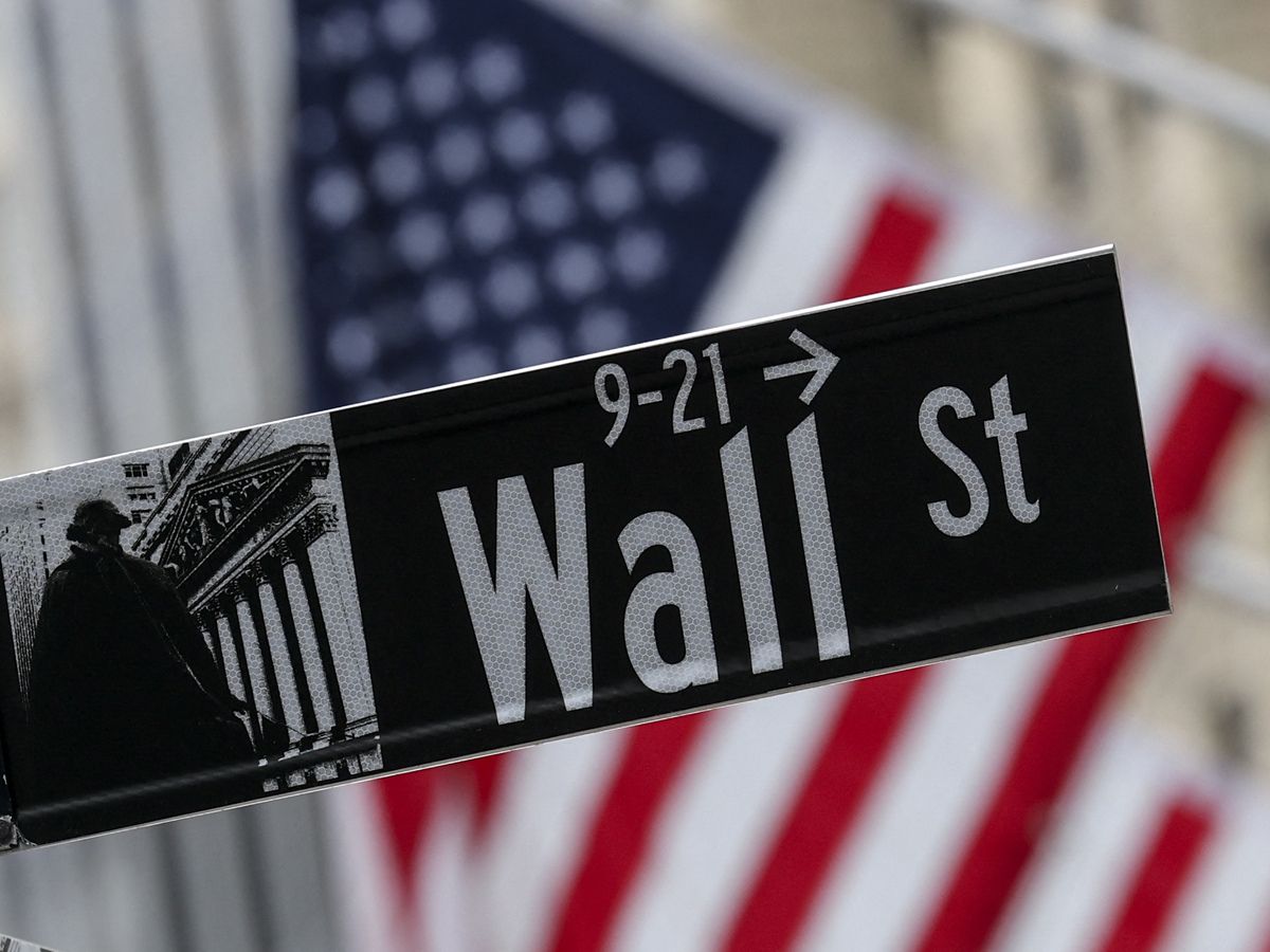 The American flag flies behind a Wall Street sign near the New York Stock Exchange (NYSE) in New York City on April 22, 2026