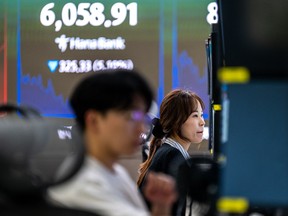 Dealers work near an electronic screen showing South Korea's benchmark stock index (KOSPI) in a dealing room at the Hana Bank headquarters in Seoul on October 13, 2026. Seoul, Tokyo and Taipei led losses across Asian stock markets on October 13 as technology firms plunged on fresh worries about the outlook for the AI investment boom, with traders preparing for a crucial earnings season and release of key US data