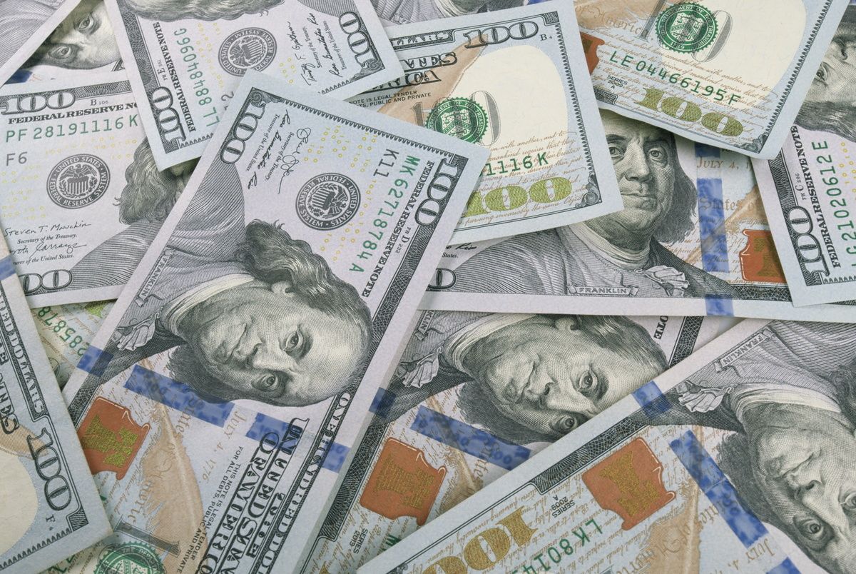 An up-close view displaying scattered U.S. dollar bills in a variety of denominations, highlighting wealth