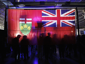 Attendees are silhouetted in front of an Ontario flag during a campaign rally for for Doug Ford, Ontario's premier, in Toronto, Ontario, Canada, on Wednesday, May 4, 2022.