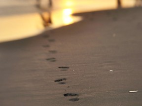 A beach goer leaves footprints in the sand on the beach as the sun goes down over the Spanish costal city of Marbella on September 1, 2009.