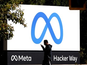 A pedestrian walks in front of a new logo and the name 'Meta' on the sign in front of Facebook headquarters on October 28, 2021 in Menlo Park, California.