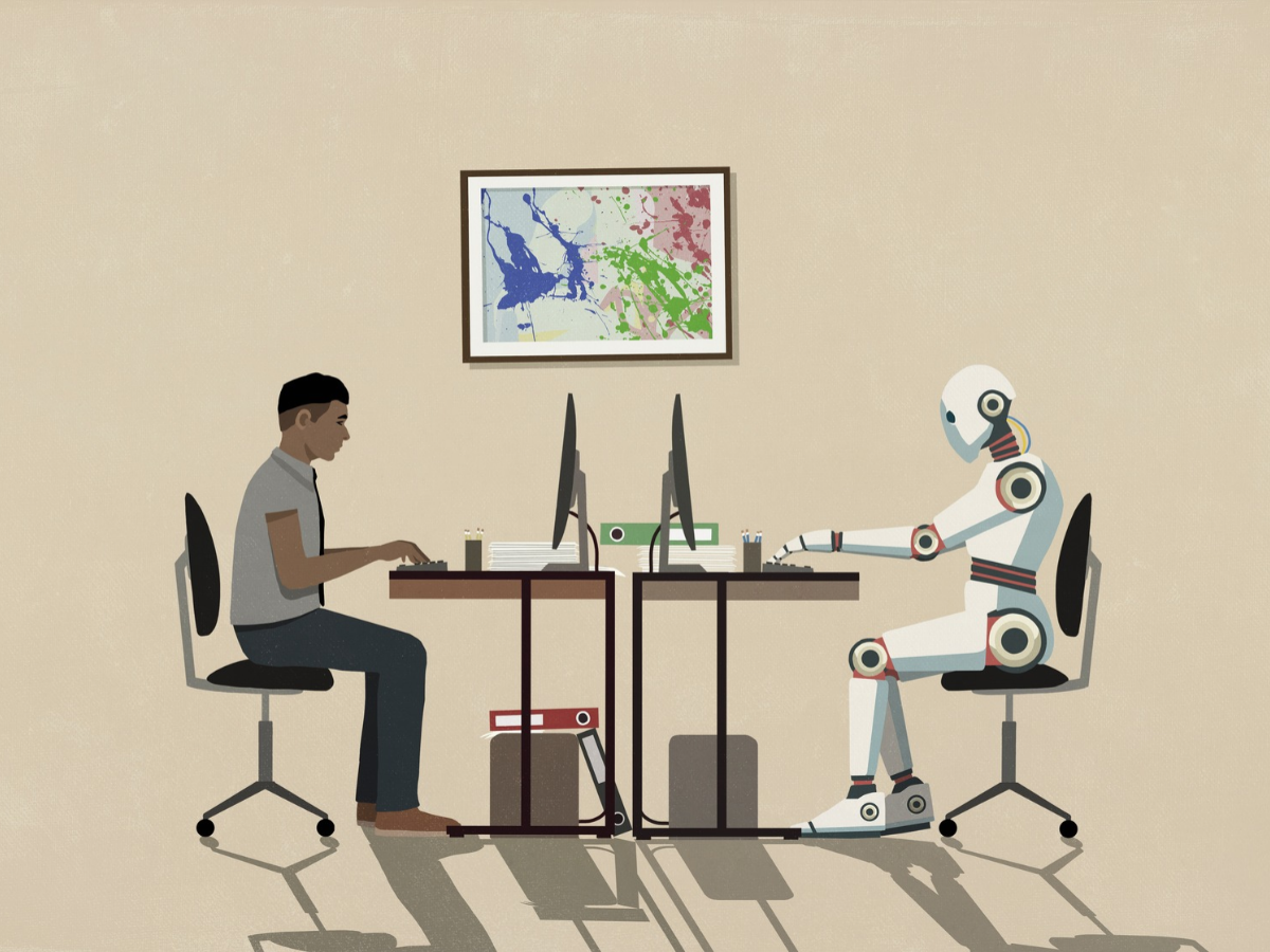 Man and humanoid robot working face to face at computers