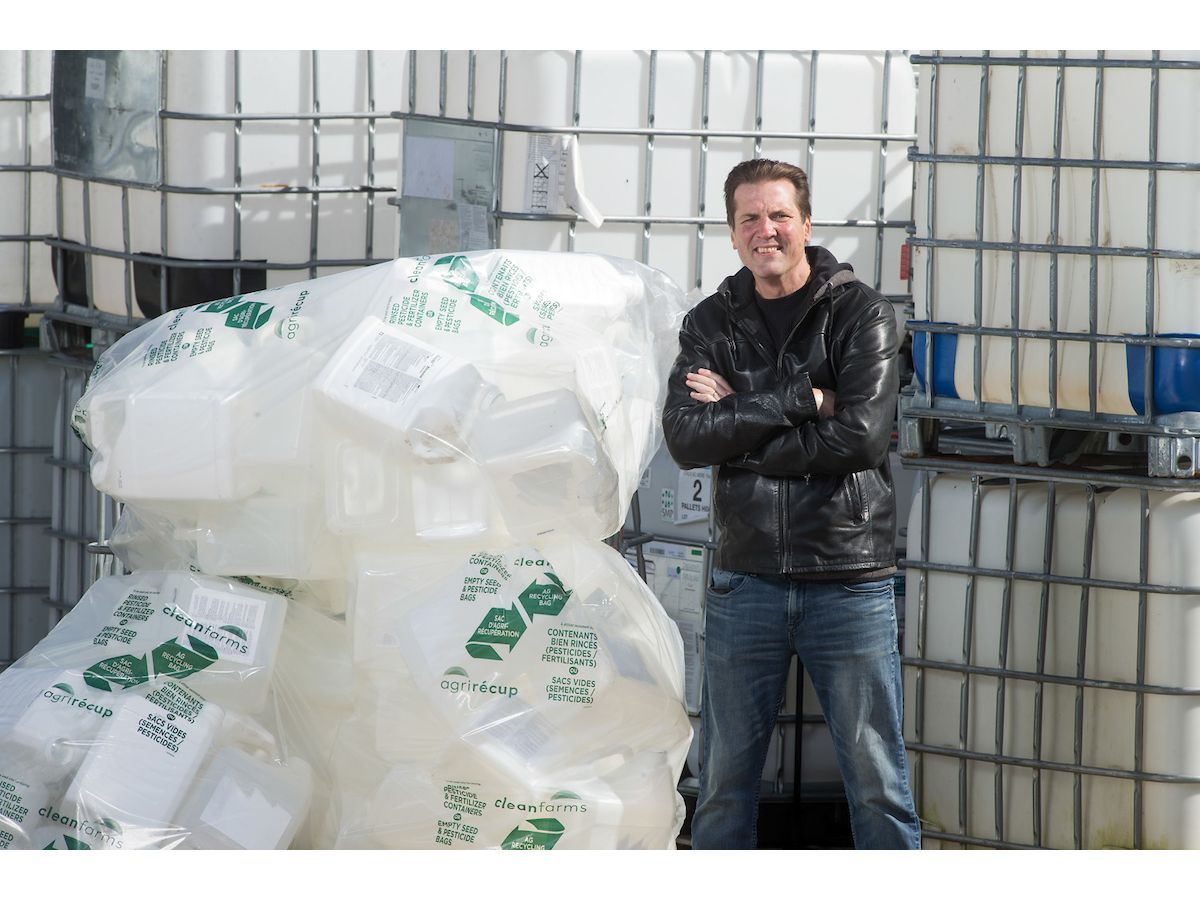 Barry Friesen, Recipient of RCA's Rs of Excellence Circular Champion Recognition Award alongside a sample of empty, used agricultural containers collected and ready for recycling under the Cleanfarms program.