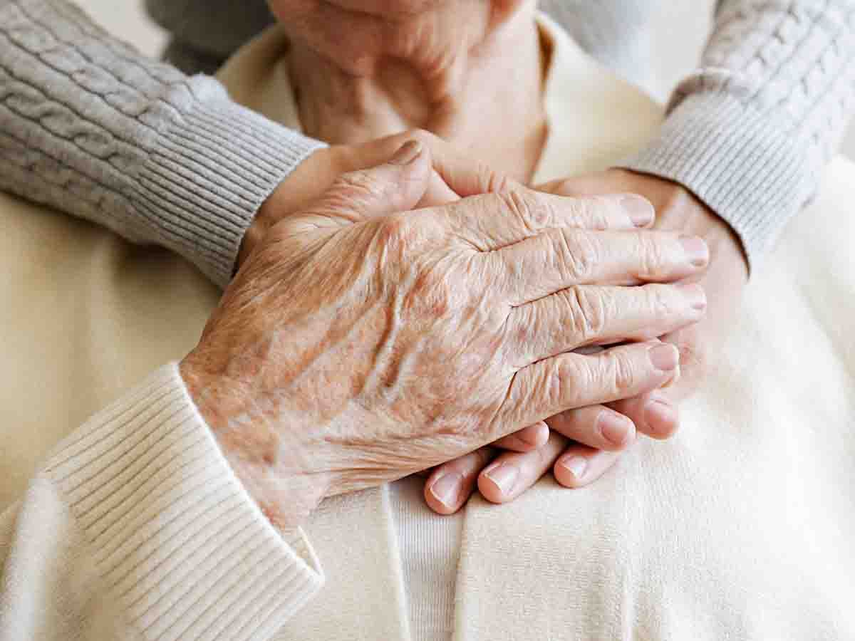 Younger person holding older persons hands