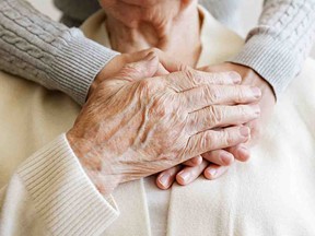 Younger person holding older persons hands
