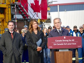From left, Scott Burrows, chief executive of Pembina Pipeline Corp. and Alberta Premier Danielle Smith look on while Prime Minister Mark Carney speaks during an announcement that the Pacific Link has been listed as a project of national interest, in Fort McMurray, Alta. on Oct. 1, 2026.