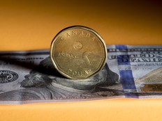 A Canadian one dollar coin with a U.S. one hundred dollar banknote. The Canadian dollar recently touched an 18-month low.