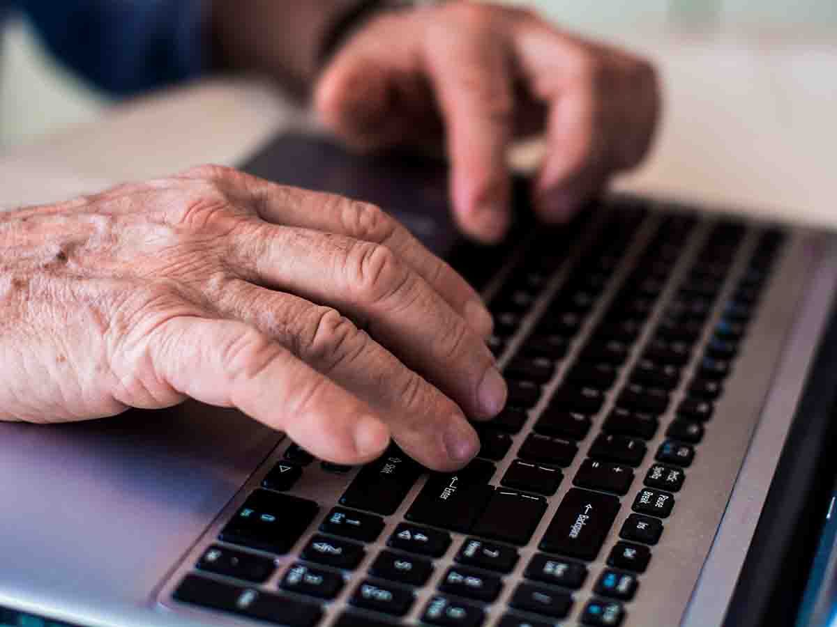 Older pair of hands typing at keyboard