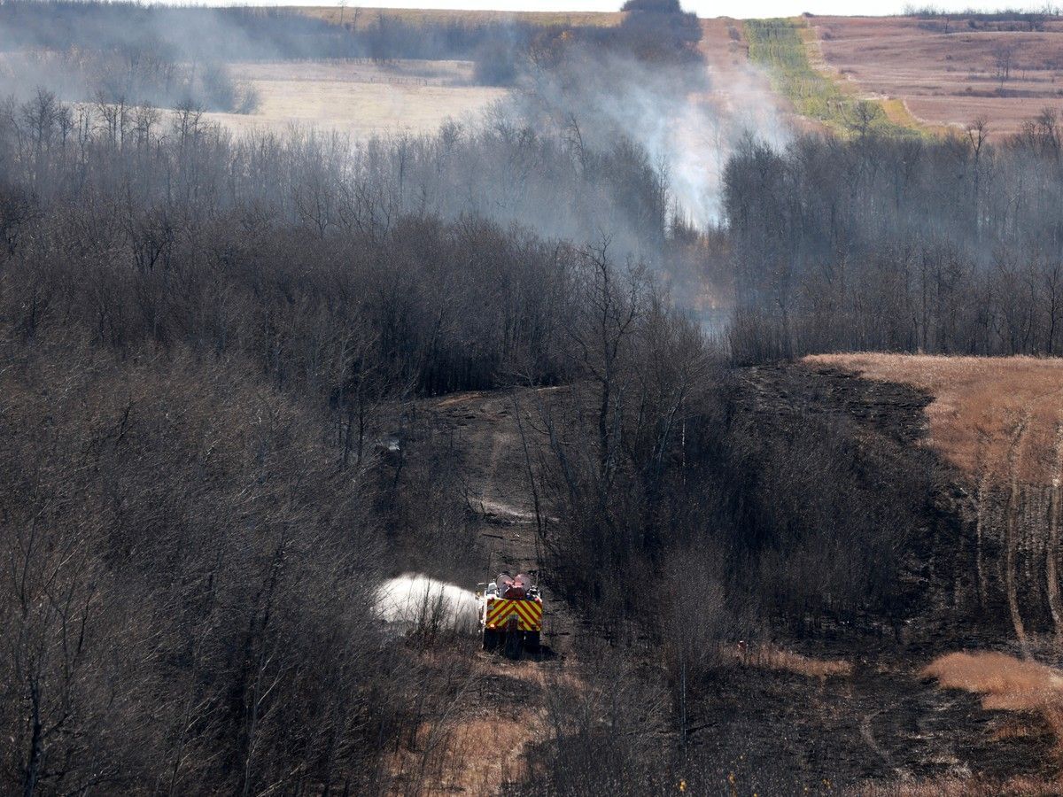 Canadian Forces fire trucks extinguish hot spots on the edge of Canadian Forces Base Wainwright on Oct. 18, 2026. Although there are oil and gas wells in the area, they were not involved in the fire.