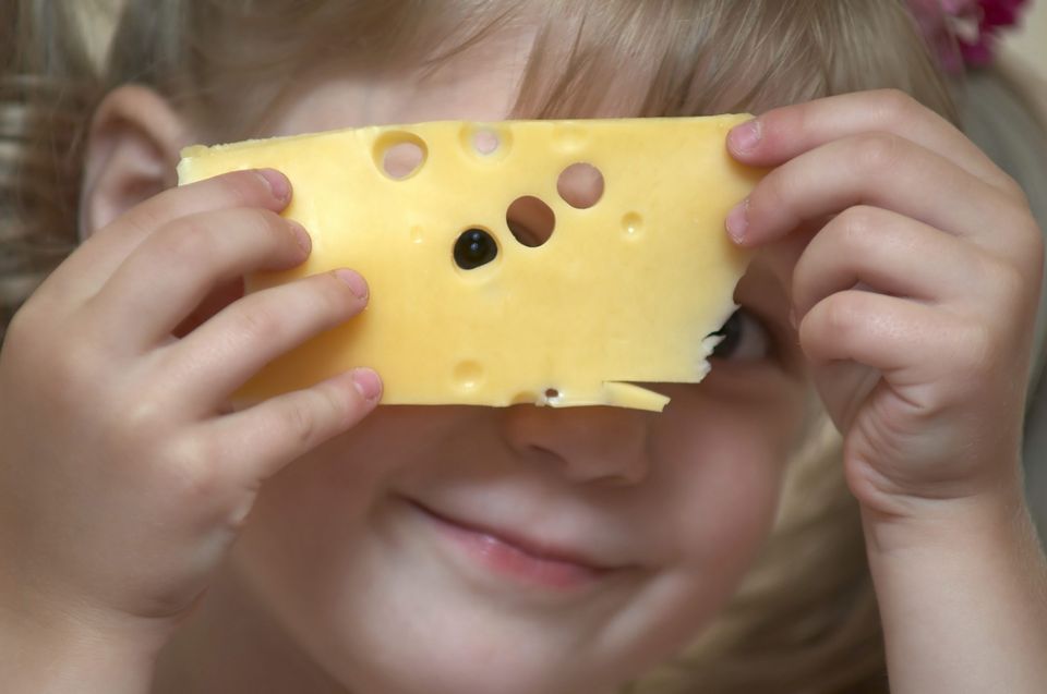little girl looking through hole in cheese