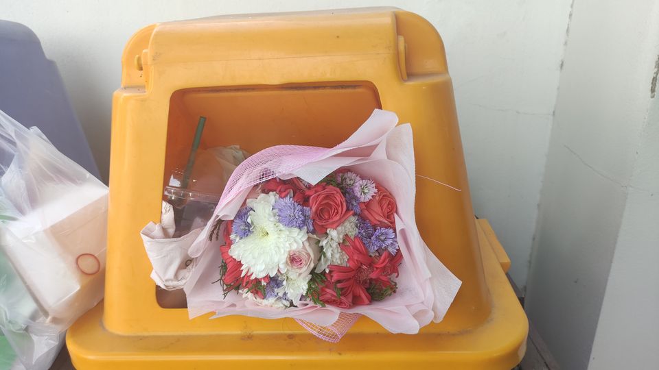 Bouquet of flowers thrown in a yellow trash can
