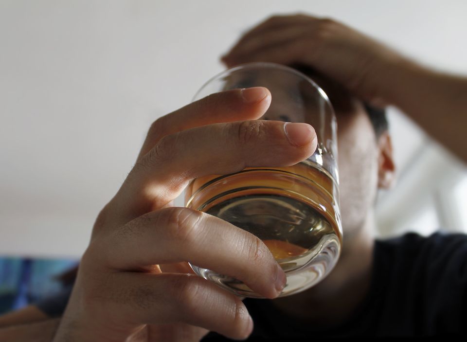 man holding glass of liquor, long angle
