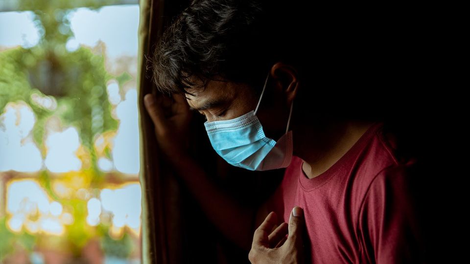 An Asian man wearing a mask has a side effect after suffering from COVID-19.