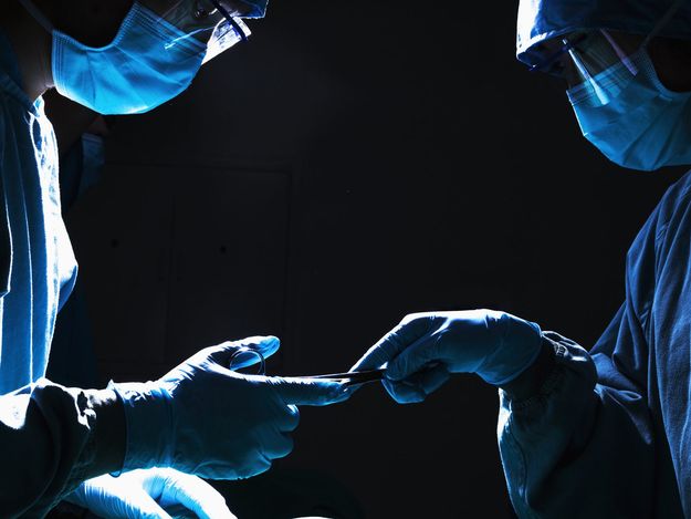 Surgeons passing surgical equipment in the operating room, dark