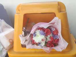 Bouquet of flowers thrown in a yellow trash can