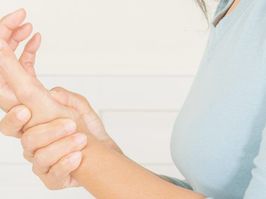 woman holding hand in pain from lupus