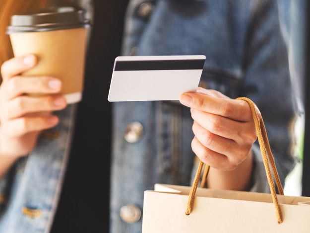 A woman holding shopping bags , credit card and coffee cup