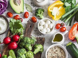 Balanced healthy diet food background in a Mediterranean style. Fresh vegetables, wild rice, fresh yogurt and goat cheese on a light background, top view. Flat lay