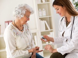 Young female doctor making diabetes blood test on senior woman