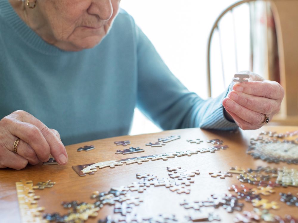 close up of senior woman relaxing with jigsaw puzzle at home