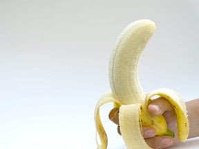 The woman's hand holds a banana, is isolated on a white background,Peel bananas on a white background.