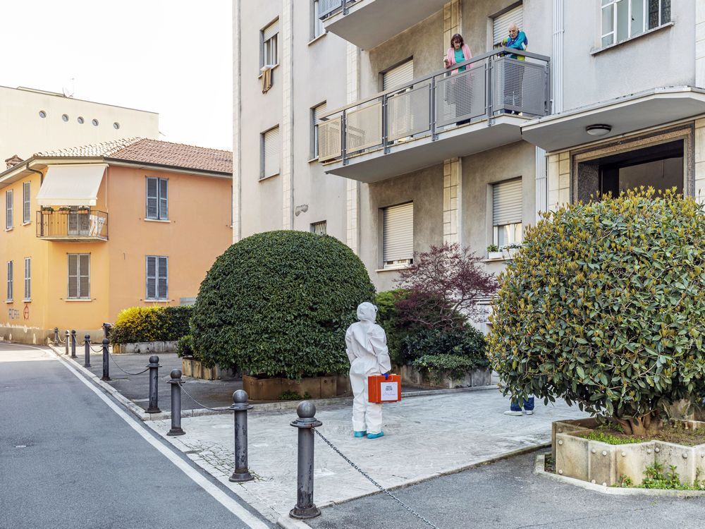 A member of the Italian Red Cross speaks with two tenants during her round of home visits to treat COVID-19-positive patients on April 3, 2020 in Bergamo, Italy.