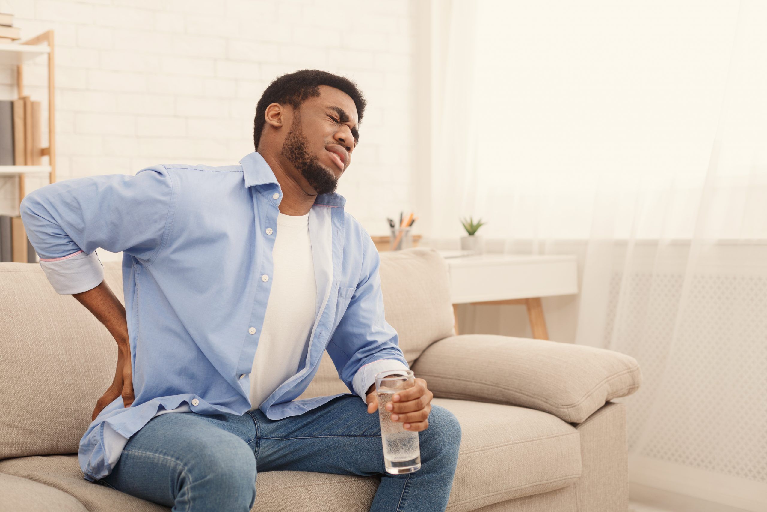 Young black man with back pain at home