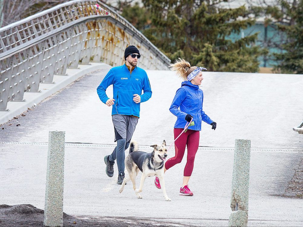 Runners are seen crossing the Corktown Footbridge as folks get outside for a walk or run along the Rideau Canal in Ottawa during the COVID-19 pandemic.