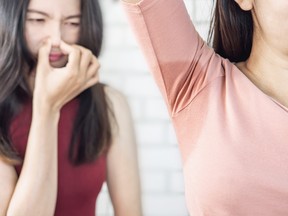 woman with arm up, wet underarm, friend holding nose