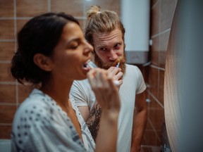 Young couple brushing their teeth together while standing in the bathroom