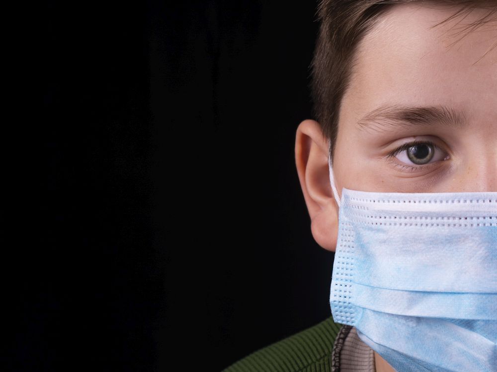 file: a child wears a surgical mask.