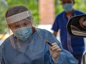 A health worker shows a blood sample that is to be tested for COVID-19. The pandemic has only amplified other serious health issues.