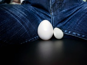 man sitting with two different sized eggs between his legs