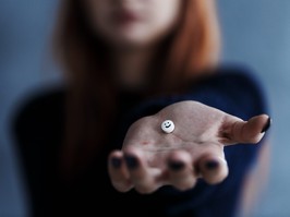 Woman holding pill with smiley face