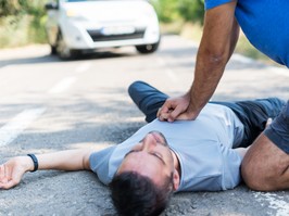 man doing CPR on man lying in street