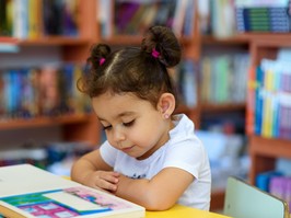 Happy child little girl reading a book.