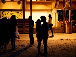 A couple kisses as people enjoy an open air party in Saint-Denis, north of Paris on August 1, 2020. Officials in many countries have linked socializing by young people to community transmission of COVID-19.