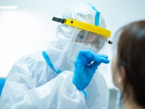 Coronavirus test - Medical worker taking a swab for corona virus sample from potentially infected woman with the isolation gown or protective suits and surgical face masks