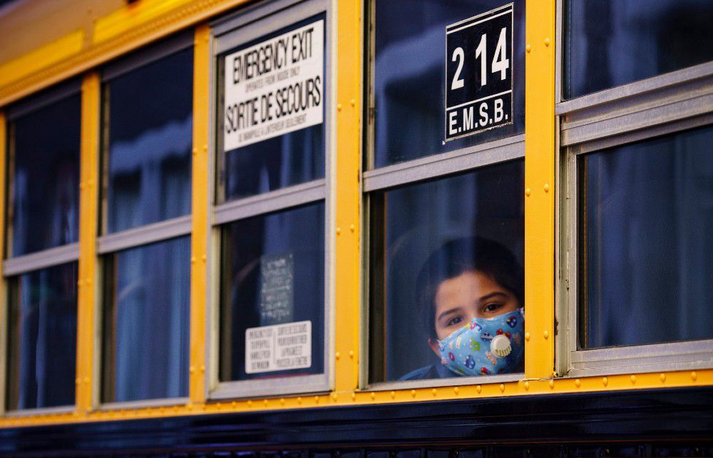 a student peers through the window of a school bus as he arrives at the bancroft elementary school in montreal, on august 31, 2020.