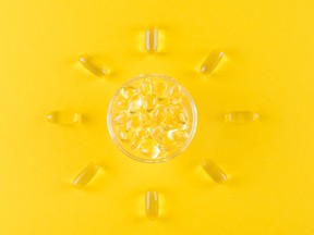 golden omega capsules like sun on yellow background, top view