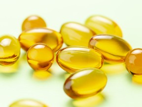 Close up of Vitamin D3 Omega 3 fish oil capsules on green background