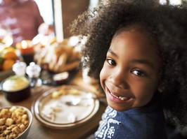 young girl smiling over a thanksgiving feast