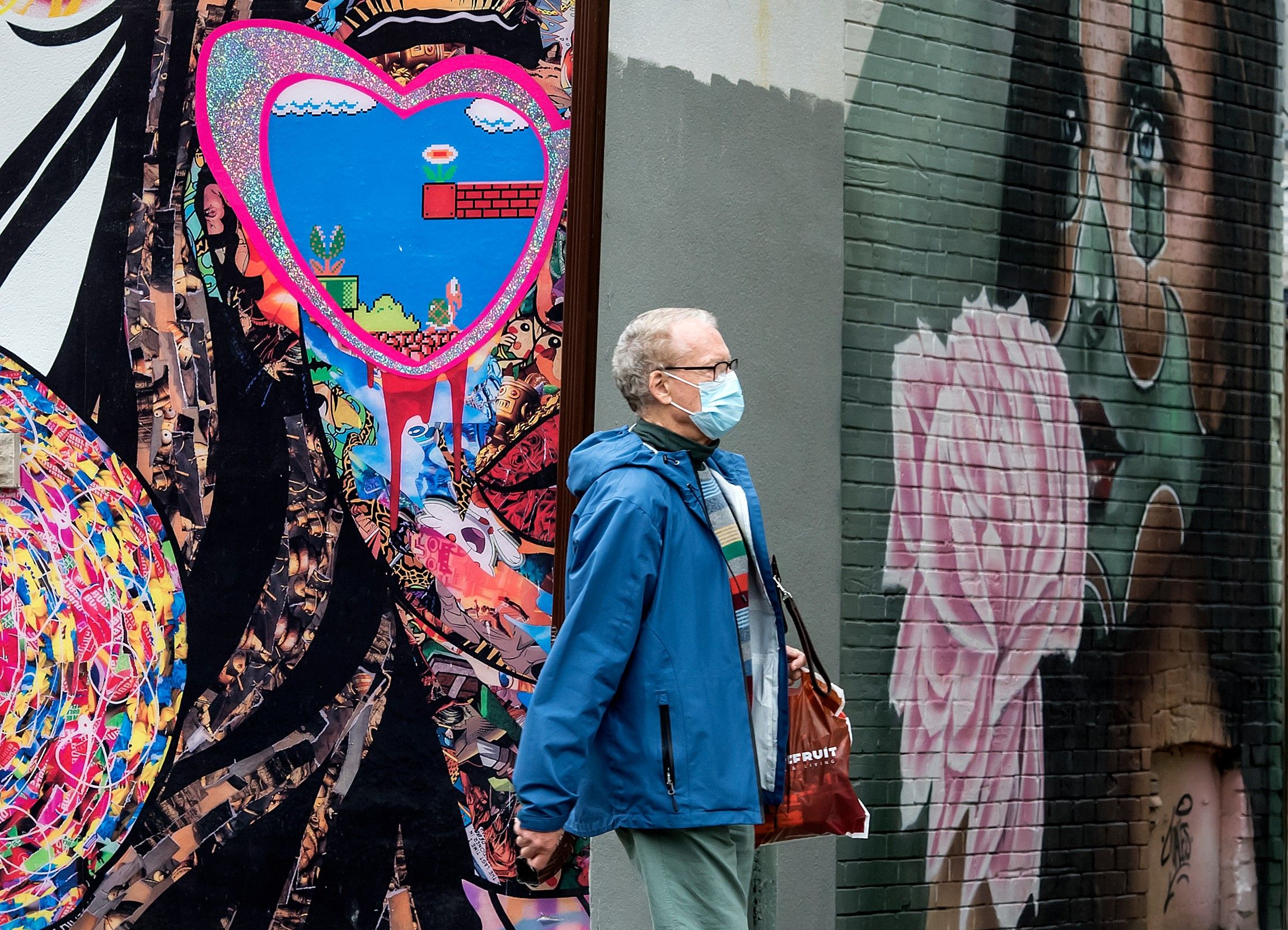 A pedestrian wearing a mask walks past a mural on Toronto’s Church Street during the Covid 19 pandemic, Thursday October 8, 2020