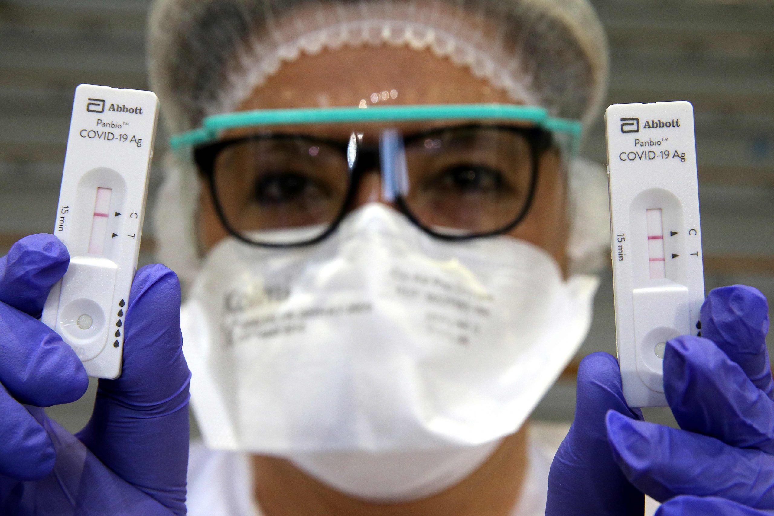 A health worker shows a negative (L) and a positive (R) Covid-19 antigen rapid test on December 17, 2020 at the gymnasium of Vrigne-aux-Bois, northern France, near Charleville-Mezieres as the city launched a mass drive to test inhabitants. 