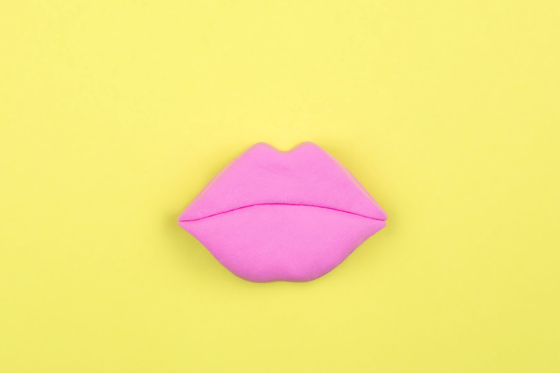 Pink lips shape, model on bright yellow background. Flat lay. Beauty concept.