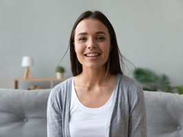 Smiling attractive young lady looking talking to camera at home