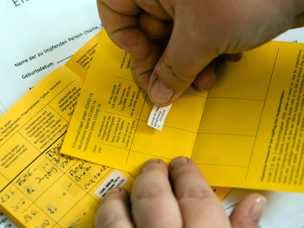 A health-care worker records a vaccination on an International Certificate of Vaccination at a hospital in Germany.