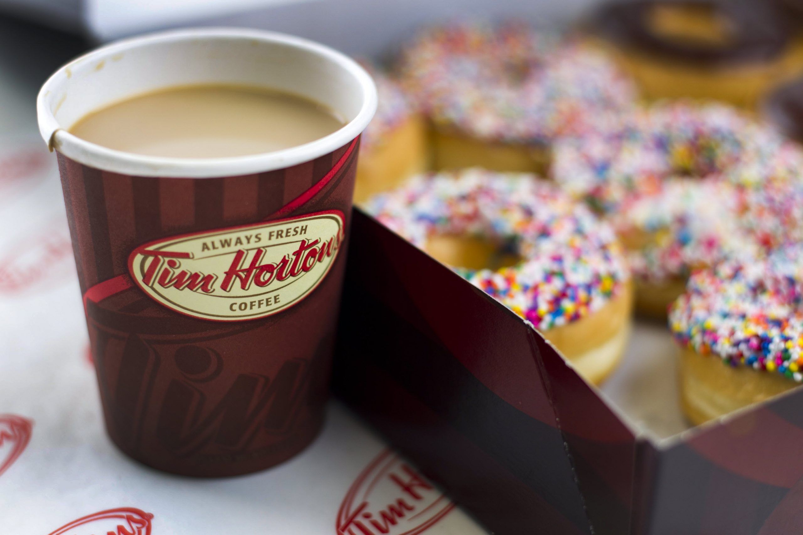 A cup of Tim Hortons Inc. coffee and doughnuts are arranged for a photograph in Toronto, Ontario, Canada, on Wednesday, Aug. 3, 2011. 