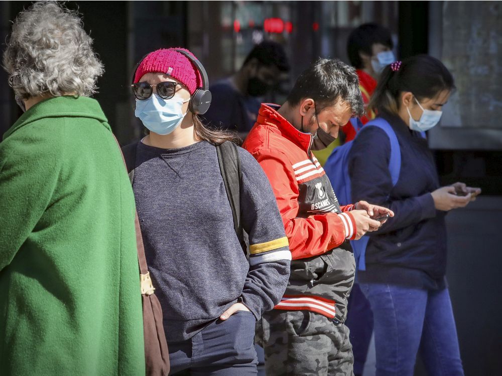 Commuters wear masks while waiting for a bus on Guy St. April 7, 2021.